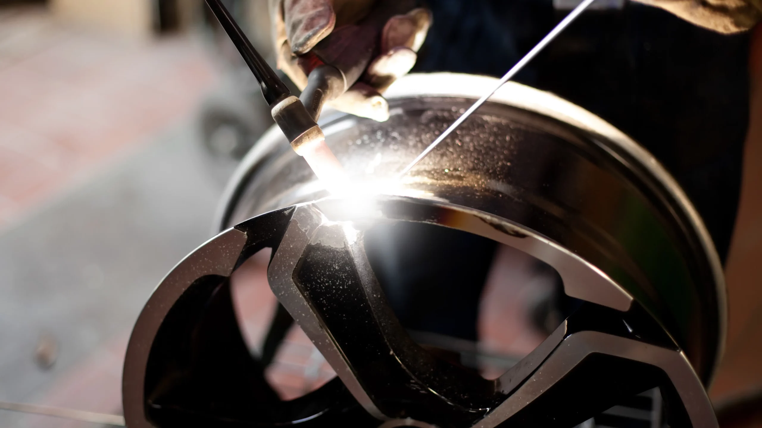 Alloy wheel being TIG welded during a professional repair